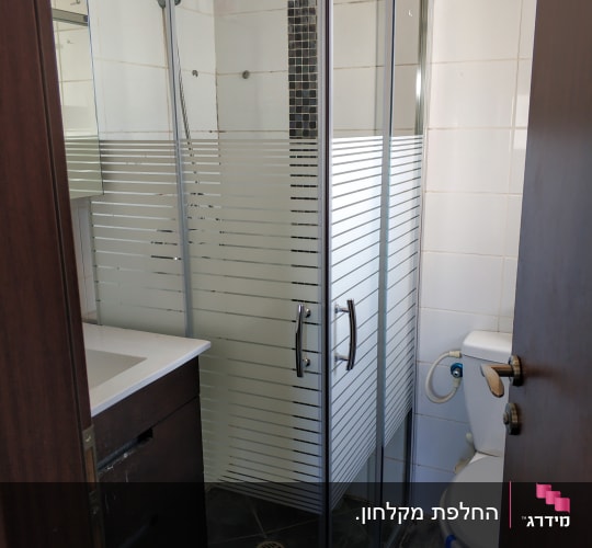 מקלחון פינתי מותקן עם דלתות הזזה מזכוכית פסים בחדר רחצה
